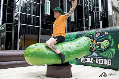 A rider clings to the new mechanical pickle at the Picklesburgh festival’s 10th anniversary in Downtown Pittsburgh. The ride, modeled after a mechanical bull, is part of the festival’s milestone celebration and symbolizes its evolution from quirky local event to national cultural phenomenon. (Photo credit: Courtesy of Pittsburgh Downtown Partnership) A rider clings to the new mechanical pickle at the Picklesburgh festival’s 10th anniversary in Downtown Pittsburgh. The ride, modeled after a mechanical bull, is part of the festival’s milestone celebration and symbolizes its evolution from quirky local event to national cultural phenomenon. (Photo credit: Courtesy of Pittsburgh Downtown Partnership)