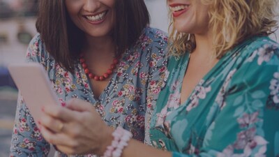 Two women smile as they look at a phone together.
