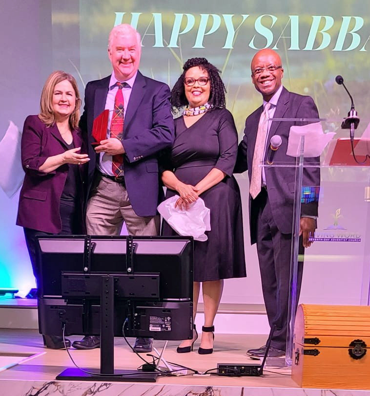 Priority Partners representatives accept the Impact of Excellence Award on stage.