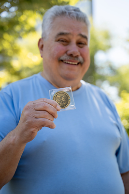 Joseph holds the 8,000th coin presented to patients of ProCure Proton Therapy Center after completion of treatment.