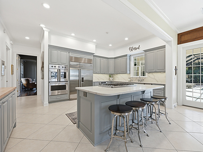 A bright and airy kitchen sits at the heart of the single-story residence. An adjacent, walk-in pantry (not pictured) offers plenty of room for storage, in addition to a coffee bar. FLLuxuryAuction.com.