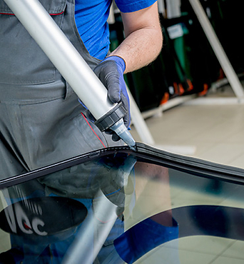 An employee secures the glass in place on a frame using a glue applicator. 